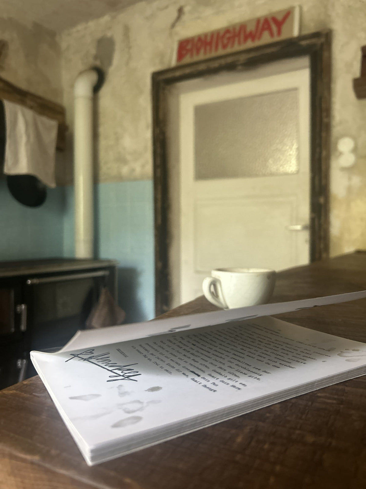 Aufgeschlagenes Buch „Create from your Heart“ vor einer Tür mit BIOHIGHWAY-Schild, daneben eine Kaffeetasse