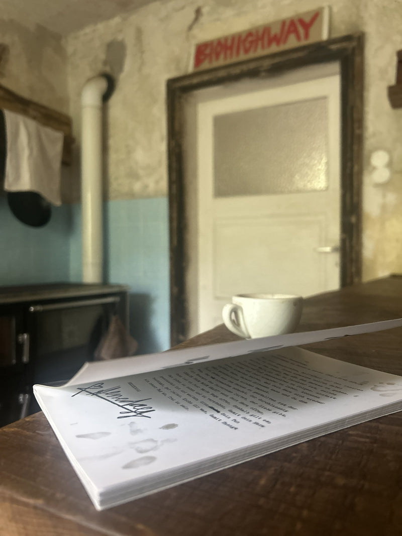 Aufgeschlagenes Buch „Create from your Heart“ vor einer Tür mit BIOHIGHWAY-Schild, daneben eine Kaffeetasse